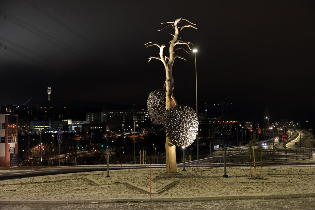 Iloharjun vanhasta männystä toteutettu taideteos. Korkea runko ja kaksi isoa männynkäpyä kohoavat keskelle kiertoliittymää Savilahdessa.