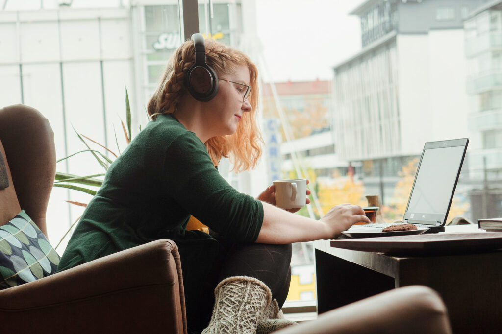 Nainen selaa tietokonetta kahvilassa.