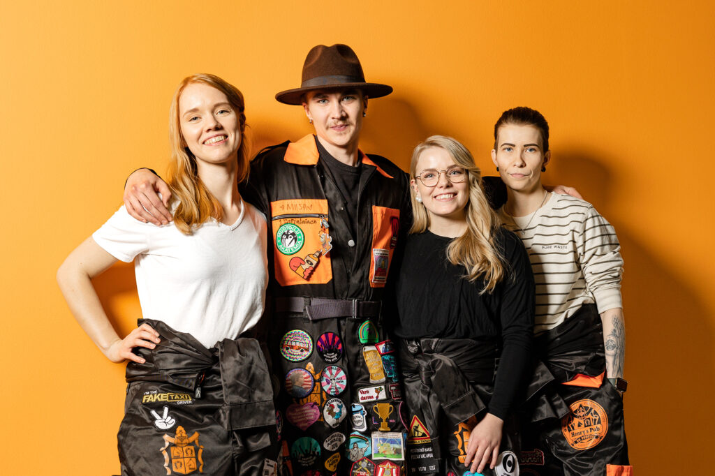 Neljä haalaripukuista opiskelijaa nojaa toisiinsa ja nauraa.