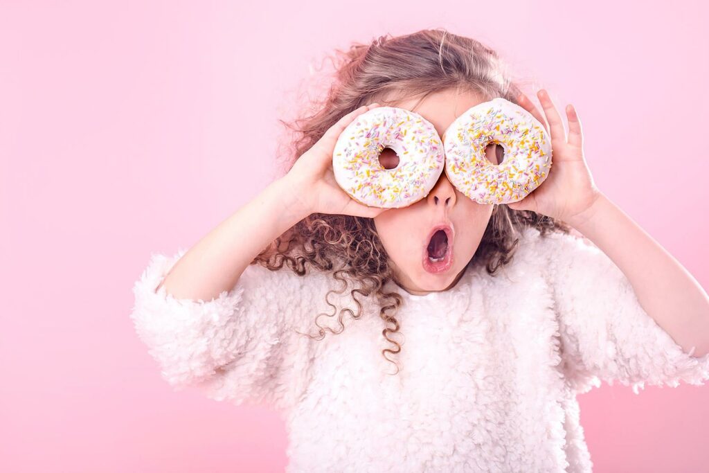 Tyttö pitää donitseja silmien edessä.